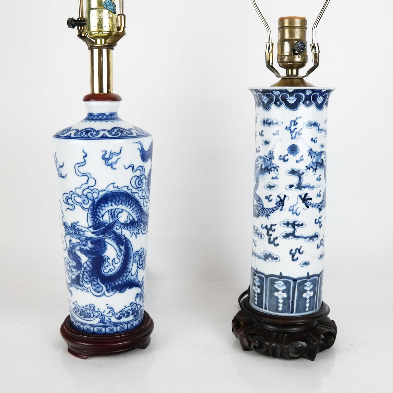 Two Chinese Blue & White Porcelain Lamps: Two Chinese blue and white porcelain lamps, the vases each with dragon decoration mounted on carved wood bases. [Taller: 23 3/4" H x 5 1/2" Diam.]. In good condition with minor wear.
