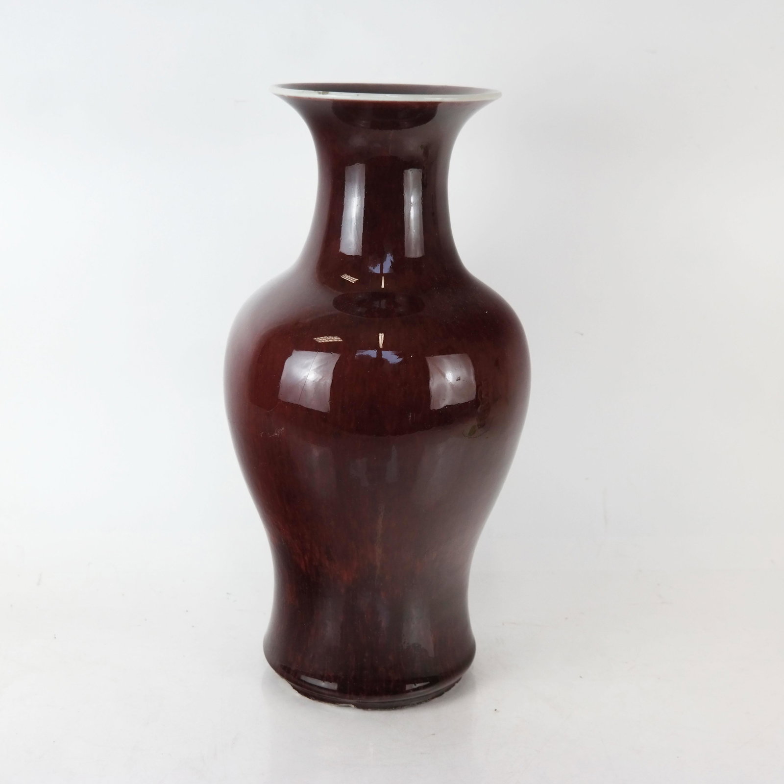 Chinese Sang de Boeuf Glazed Vase: Chinese sang de boeuf glazed vase of baluster form with striated color, unmarked. [16" H x 9" Diam.]. Chips to rim and base.
