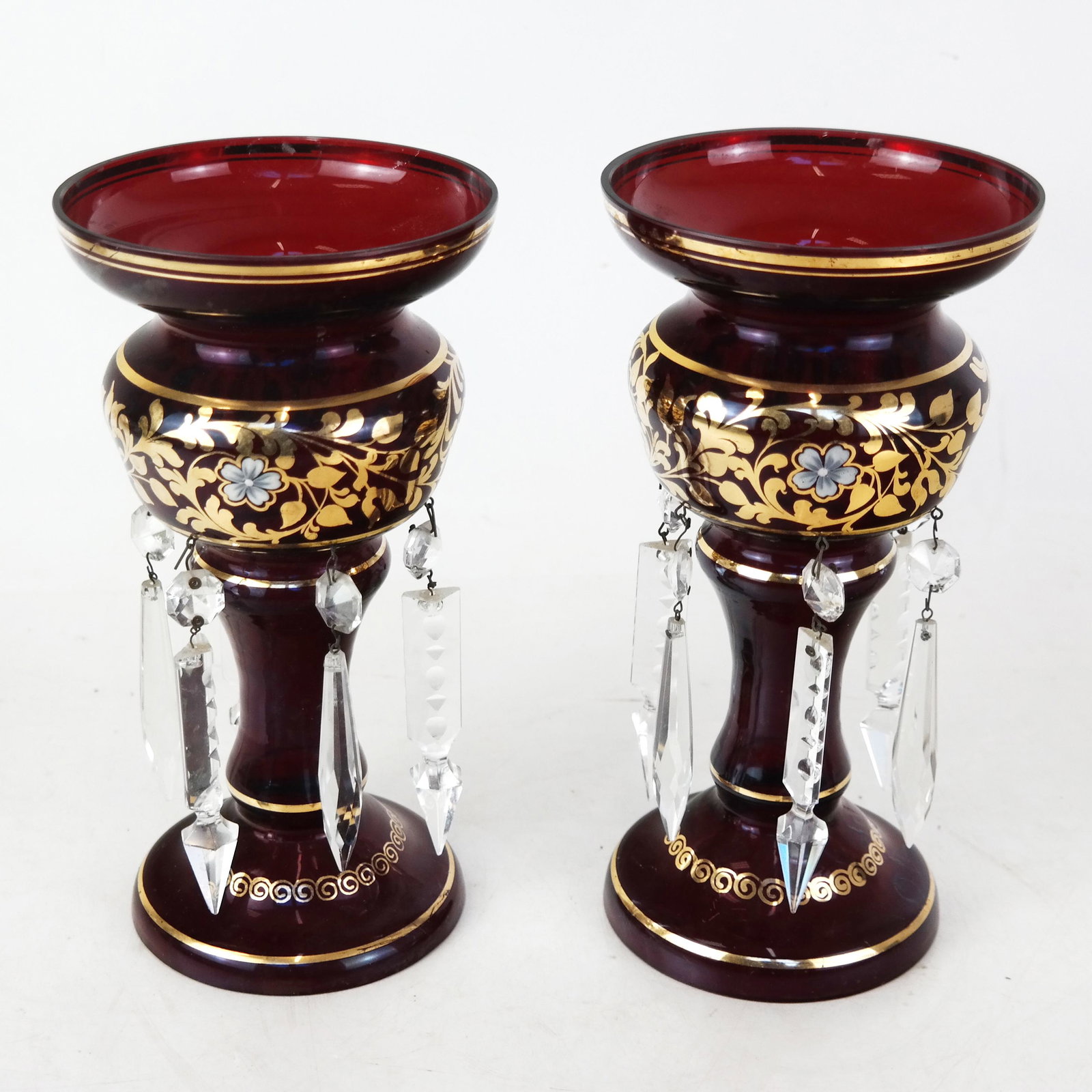 Pair of Gilt Accented Cranberry Glass Lusters: Pair of gilt accented cranberry glass lusters with pendant prisms. [9" H x 4 3/4" Diam.]. Residue, wear, chips to prisms.