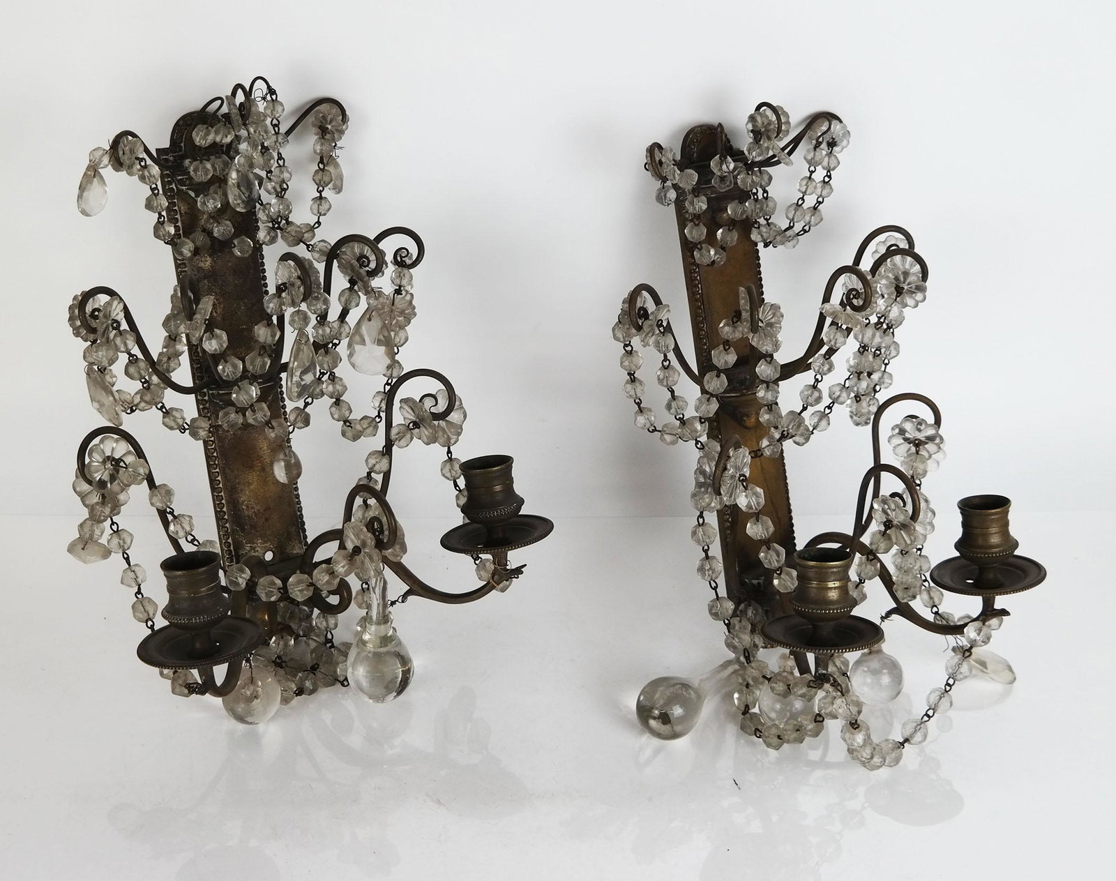 Pair of Neoclassical-Style Girandole Sconces: Pair of Neoclassical-style bronze and glass girandole sconces, having scrolling arms with pendant and swag drops. [13" H x 8" W x 6" D]. Some swags loose; oxidation; residue; wear.