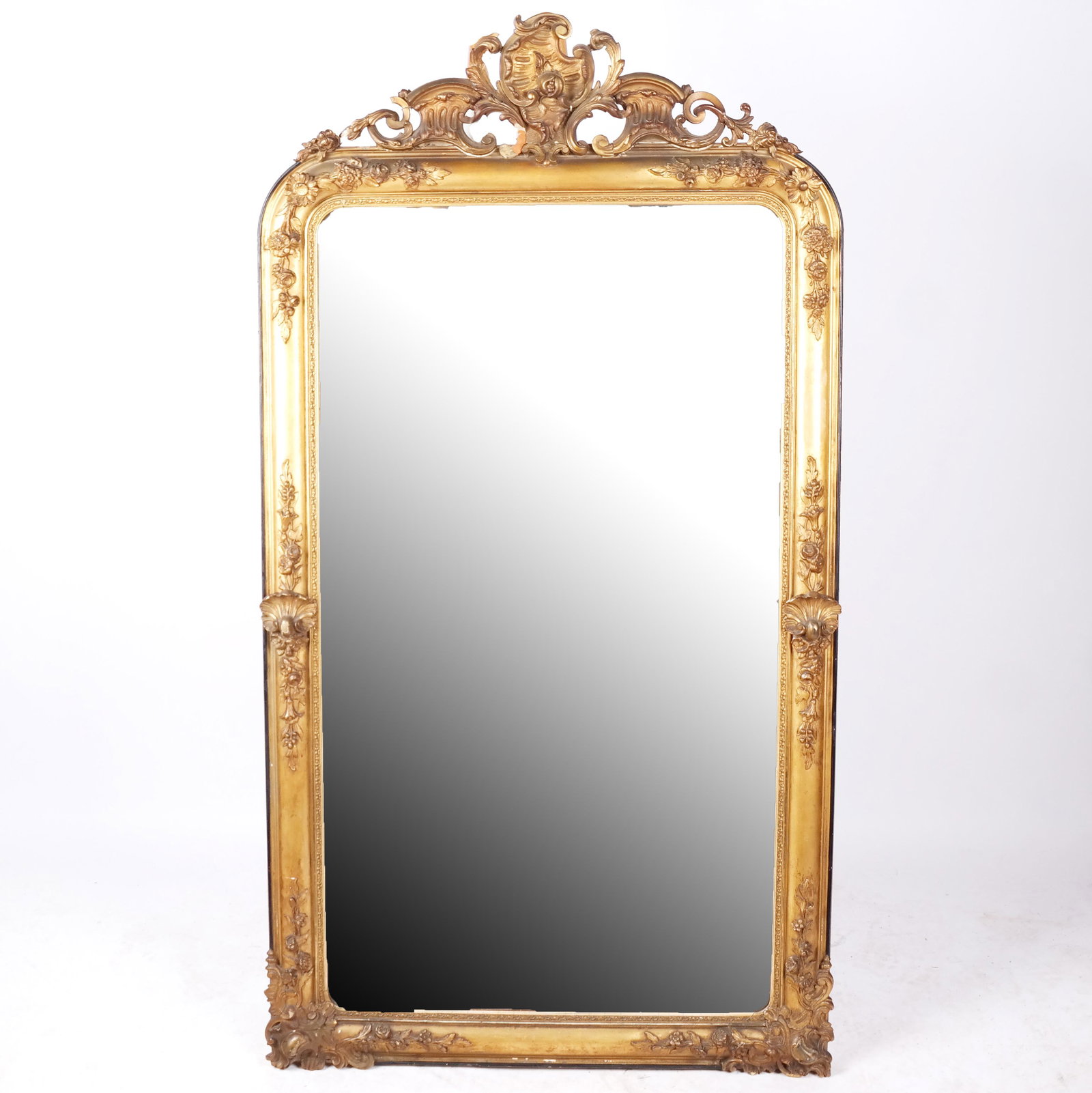 19th Century Giltwood Pier Mirror: 19th century giltwood pier mirror with floral accented rocaille crest and borders. [62 3/4" H x 34" W x 2 1/4" D]. Some wear and losses to gesso, plate probably later.