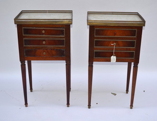 Pair of Louis LXVI Style Petite Commodes: Pair of Louis LXVI style mahogany marble top three-drawer commodes. Each bear piered brass gallery tops, bronze accents and fluted legs, tapering to brass sobot feet. As is, missing pull. 16" W x 11.2