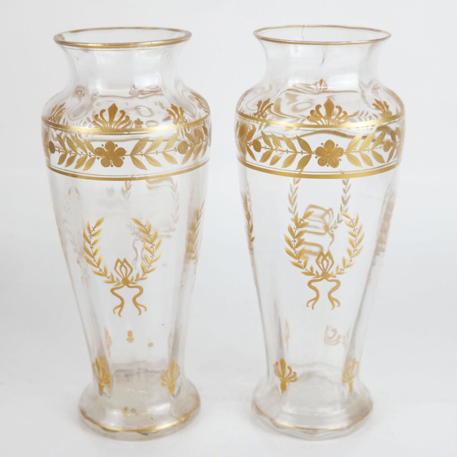 Pair of Napoleon III Parcel Gilt Glass Vases: Pair of 19th century French Napoleon III parcel gilt glass vases, overall with painted Neoclassical motifs of laurel leaf wreaths, palmettes, and floral details. One with cracked rim, both with light 