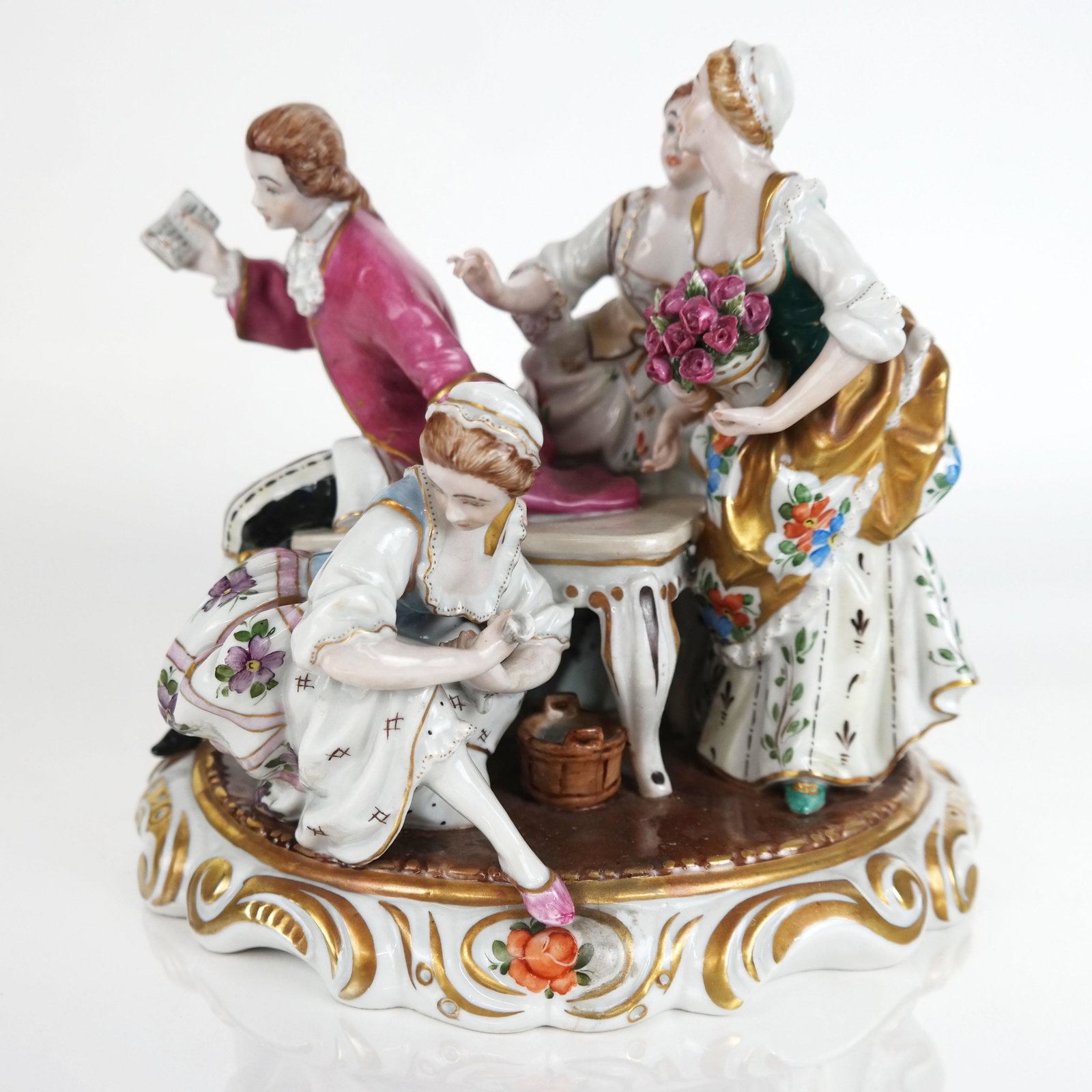 German Porcelain Figural Group: German porcelain figural group, in the Rococo taste with figures in 18th century attire, overall with parcel gilt polychrome decoration; the base with underglaze blue crossed arrows under a crown mark