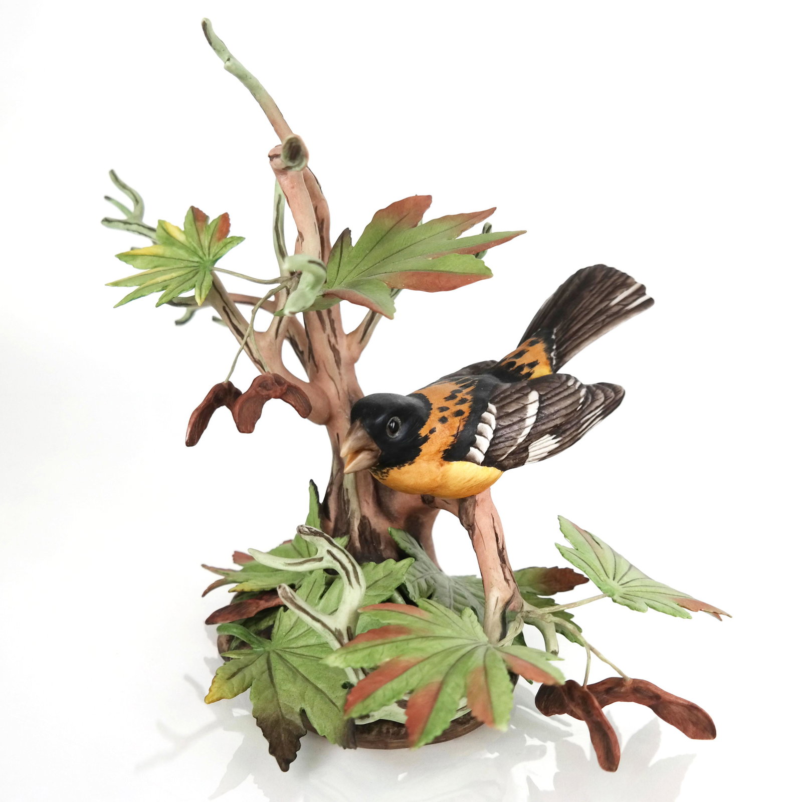Boehm Painted Porcelain & Tole Sculpture: Boehm painted porcelain and tole sculpture, modeled as a bird perched among leafy branches; marked and numbered to base. [9 1/4" H x 14" Diam.]. In overall good condition, with minor wear.
