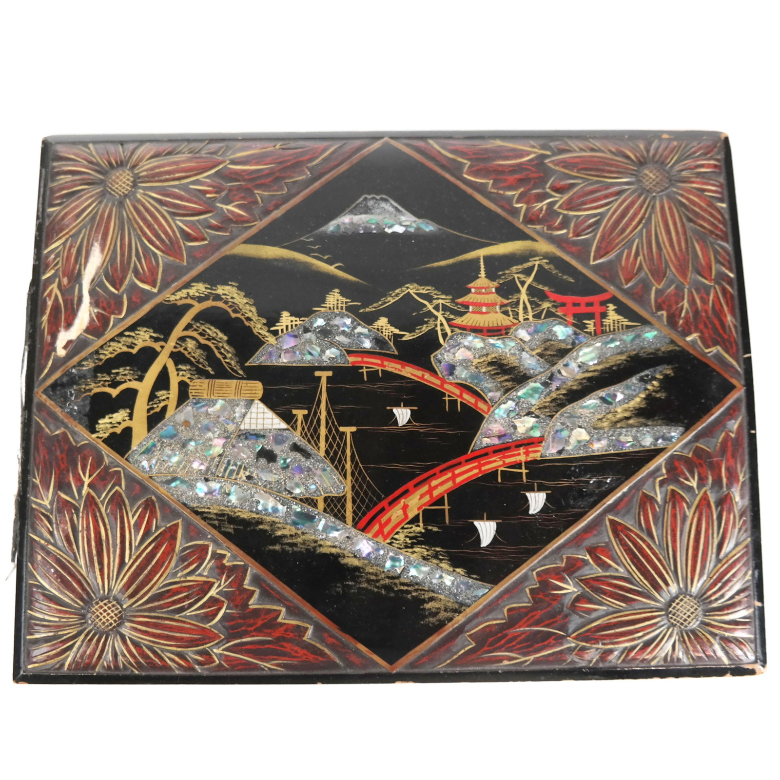 Japanese Carved & Inlaid Panel: Japanese carved and inlaid panel, having a lozenge cartouche within parcel gilt carved corners, depicting a shell inlaid village scene with bridges and pagodas before a mountain peak, possibly Mount F