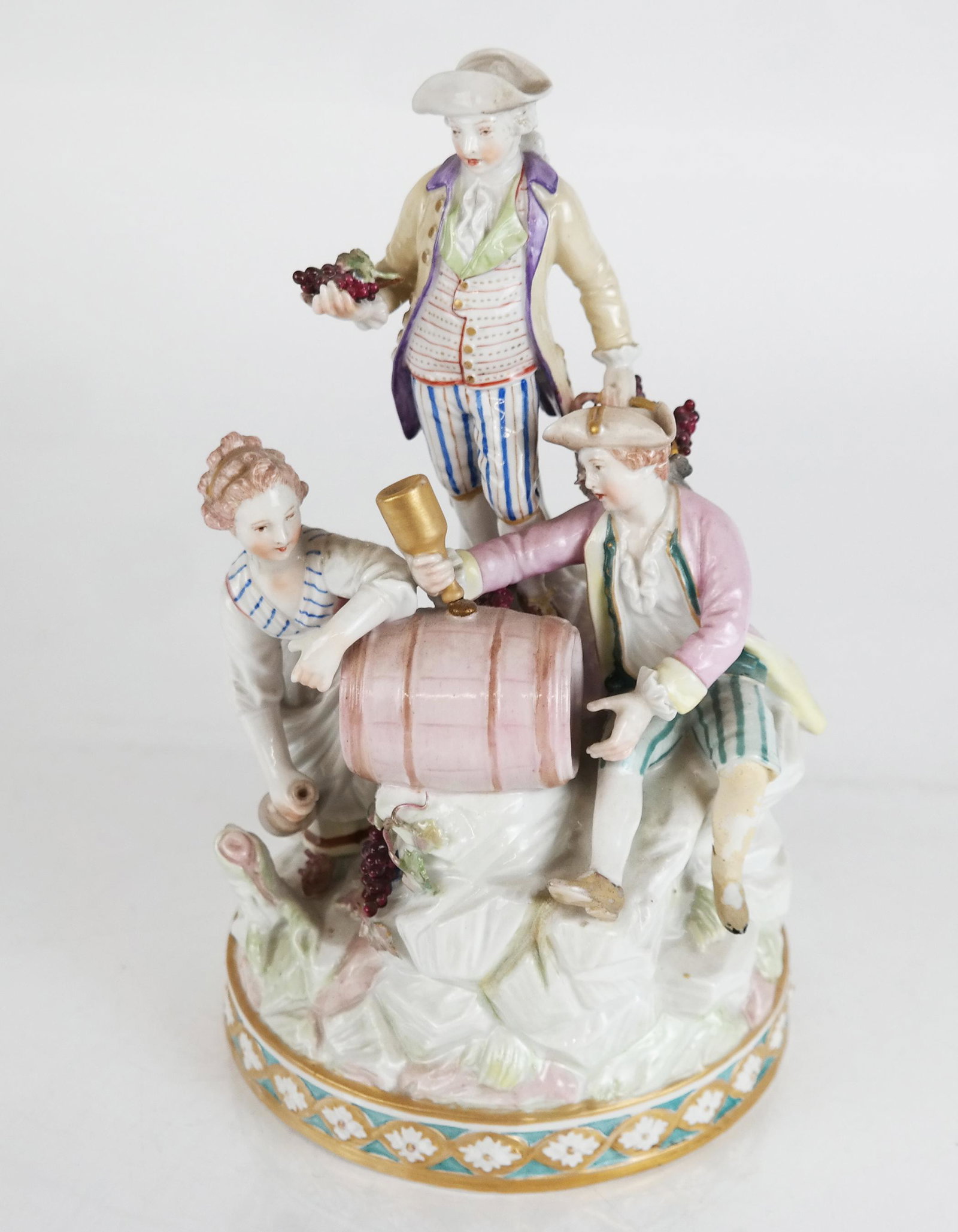 Continental Porcelain Group of Three Wine Makers: Continental porcelain group of three wine makers, after the original modeled by Michel Victor Acier (18th century); faint underglaze scepter mark. [10 1/4" H x 5" W]. Damage to rear tree stumps. Resto