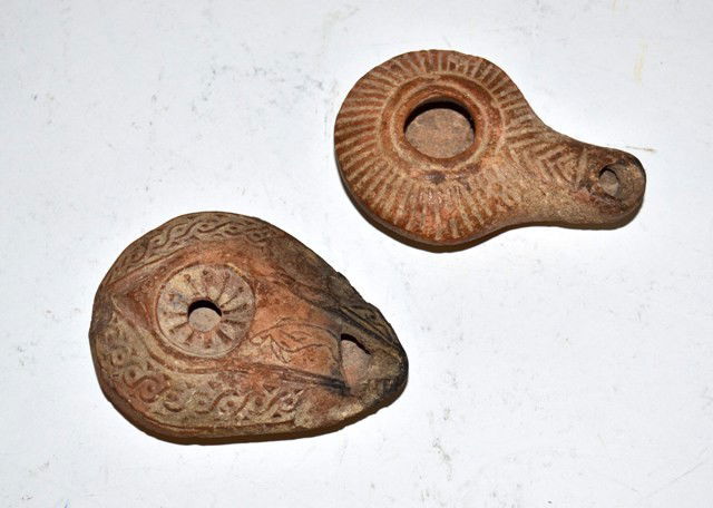 Two Antique Persian Earthenware Oil Lamps: Two Antique Persian earthenware oil lamps. One bears an incised sunburst pattern, the other a running dog motif. Bears chips and wear consistent with use. Larger: 3.75" L.
