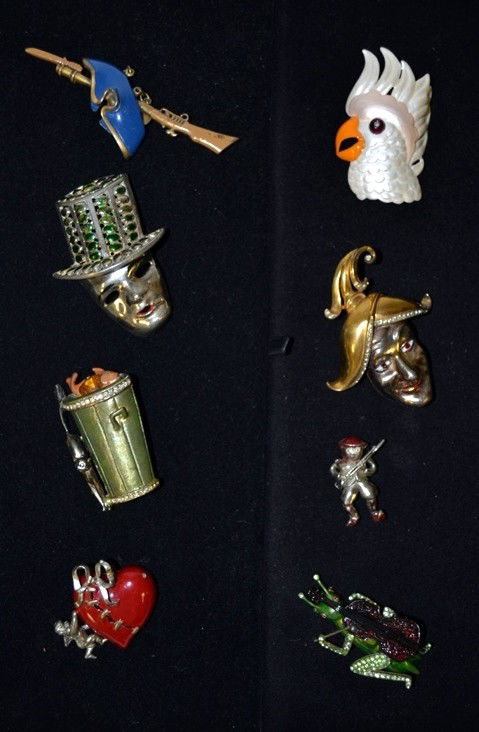 Trifari & Derosa Incl. 8 Pins: Including: a Trifari cockatoo pin, a Derosa harlequin pin, a WWI heart soldier pin, a green cricket with spring movement, rifle, and carnival mask (mask by A. Goodman & Co.), together with a garbage p