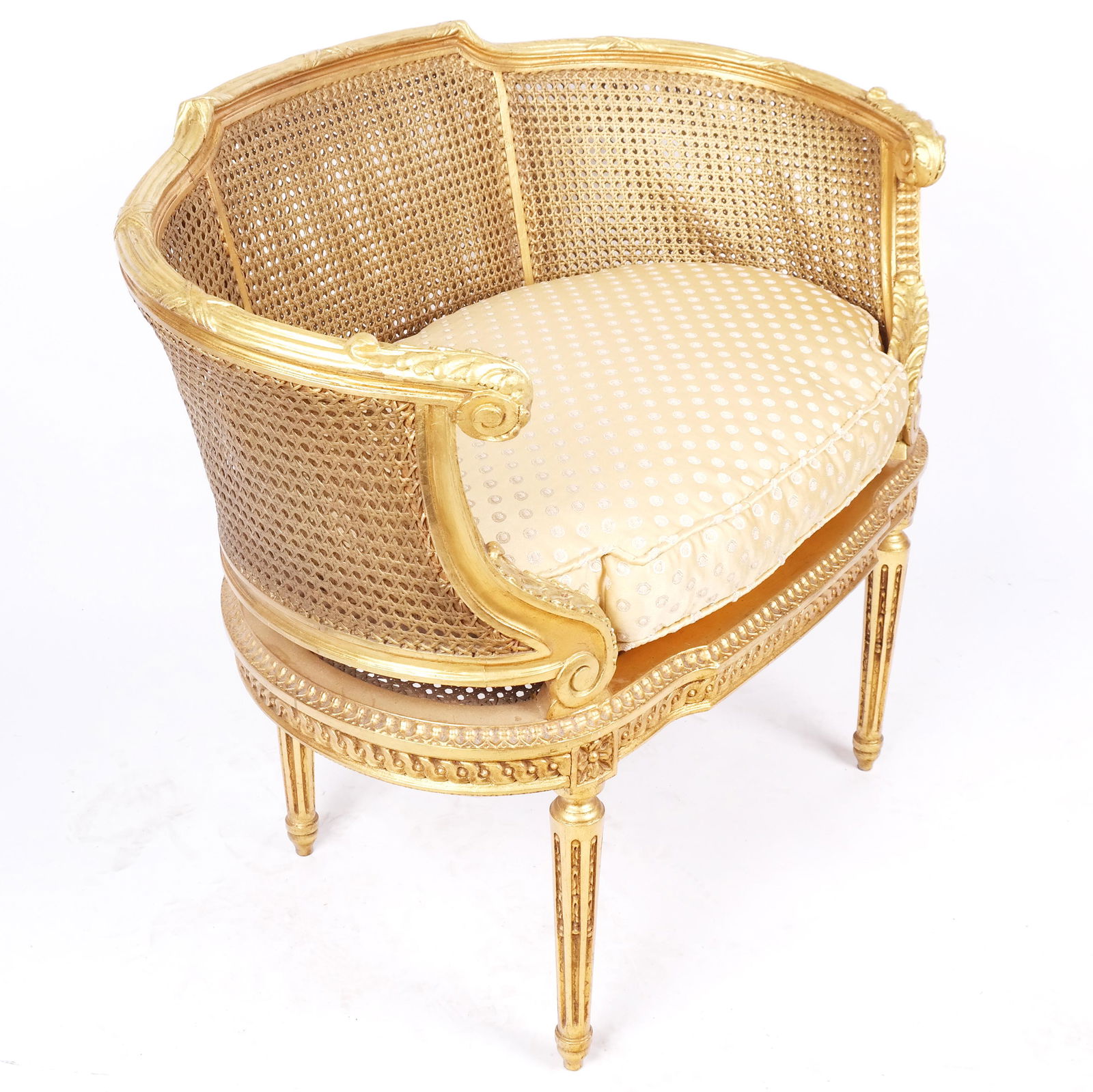 Louis XVI-Style Giltwood Bergere en Cabriolet: Louis XVI-style giltwood bergere en cabriolet of diminutive proportions, the armchair with carved details to the curved frame with caned panels, raised on tapered fluted legs; circa 1900. [31" H x 35"