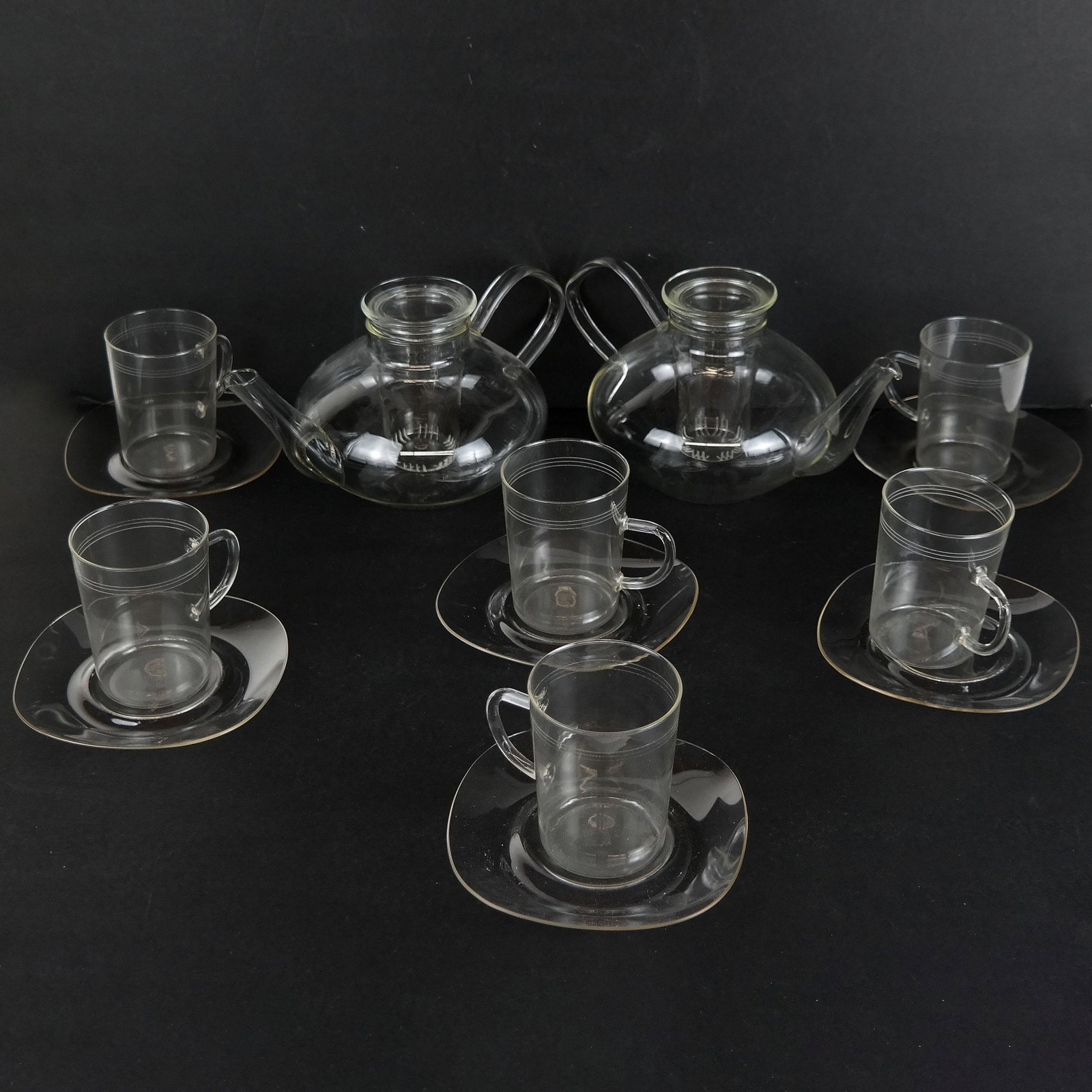 Set of Schott Jena Teapot Infusers, Cups & Saucers: A pair of German (Mainz) teapot infusers, designed by Loffelhardt in 1957, after an earlier design by William Wagen Feld (Bauhaus designer) (1900-1990); including six cups and six saucers.