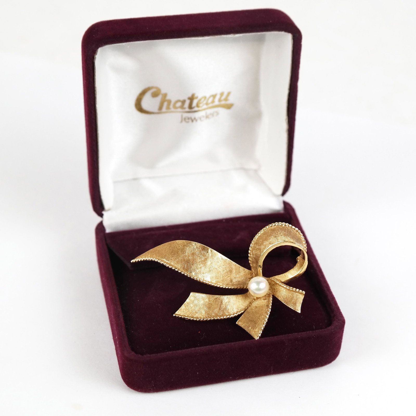 14K Yellow Gold Bow Pin: 14k yellow gold bow pin, shaped as a flowing bow with a pearl; stamped 14k. (6.1 dwt. inclusive of pearl). [2" H x 1 1/4" W].
