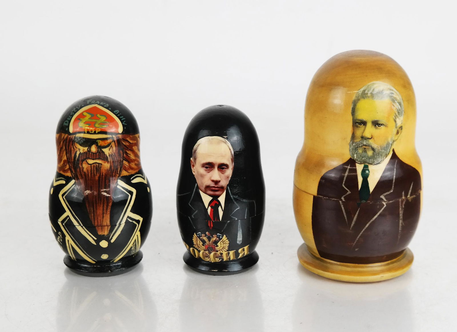 Group of Three Small Matryoshka Nesting Dolls: Group of three small Matryoshka Russian nesting dolls, comprising one of historical figures and presidents, one of Putin, and one of ZZ Top; marked Russia 2002. [Largest: 4 1/2" H x 2 3/4" W]. In good