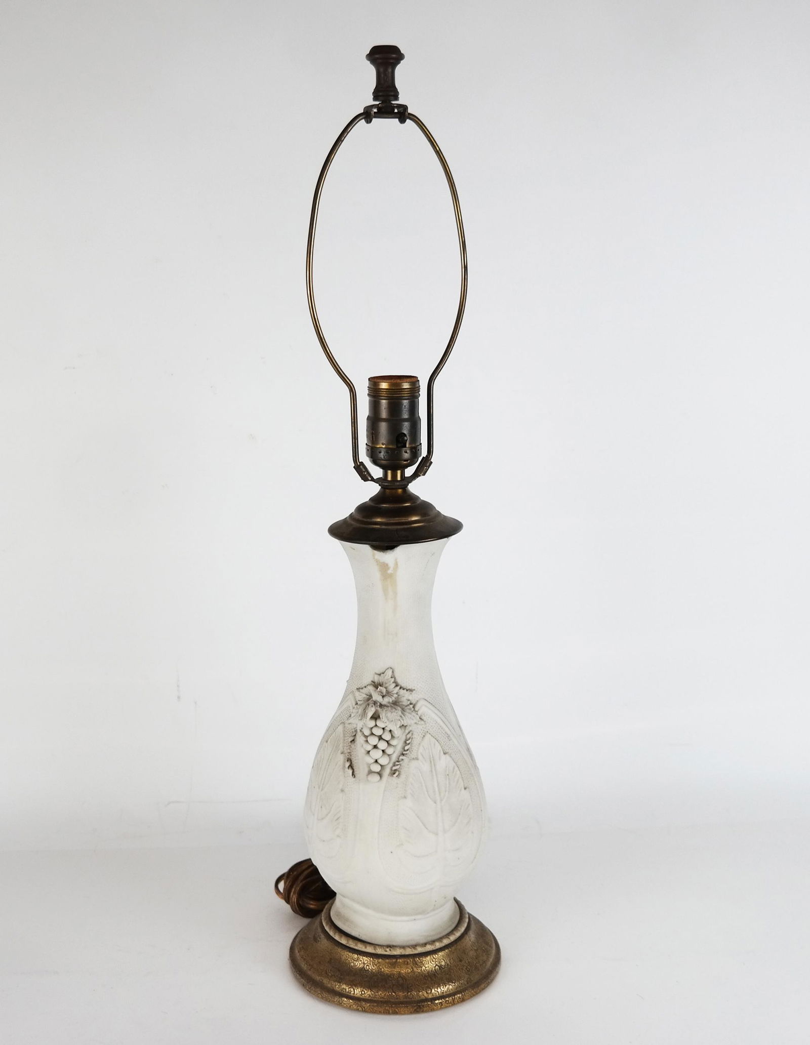 Bisque Porcelain Table Lamp: Bisque porcelain table lamp with Bacchanalian motifs of grape bunches and leaves. Breaks and restoration, losses to decoration, drill hole to bottom side.