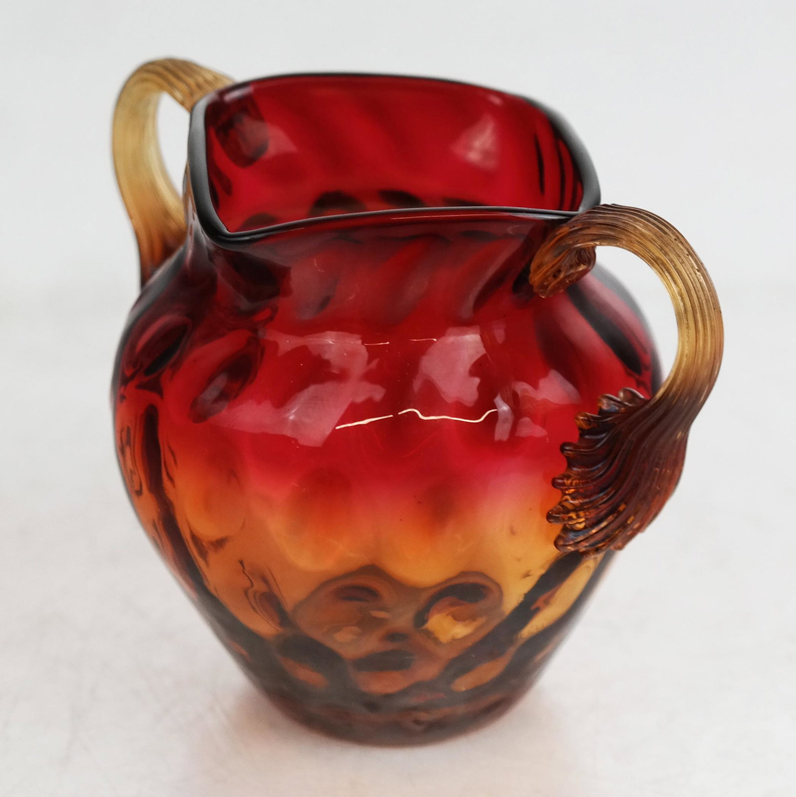 Miniature Burmese-Style "Amberina" Vase: Miniature Burmese-style "Amberina" vase, with pulled, applied handles, the internally textured glass fading from red to amber; not marked. [2 1/2" H x 3 1/4" W x 2 1/2" D].