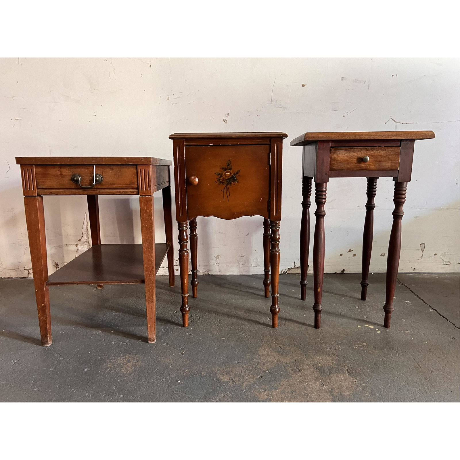 Three Tables: Three tables, two with single drawer, one with a door. [28" H x 15" W x 14" D; 24" H x 15 1/2' W x 24" D (largest)].