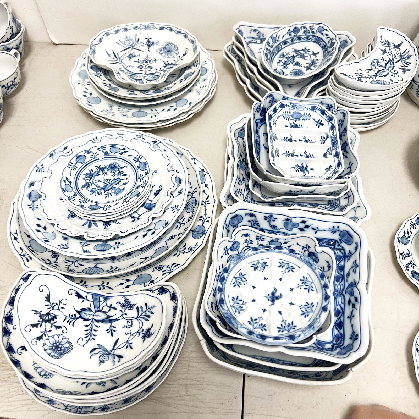 Meissen German Porcelain "Blue Onion" Serving Pcs: 50 pieces, 20th century, comprising various plates and bowls including crescent fish bone plates, square bowls, triangular dishes, platters and plates. Assembled items with various date marks to bases