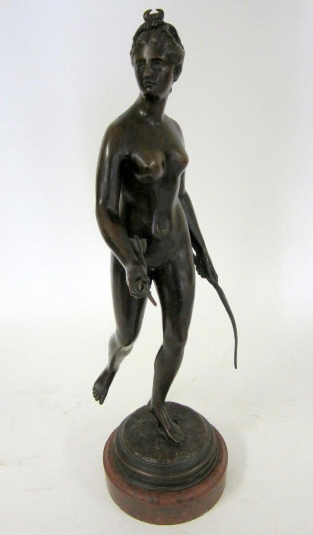 After Jean-Antoine Houdon Bronze, "Diana": Bronze depiction of Diana The Huntress with bow and arrow. Figure stands on a stepped circular base with naturalistic ground on a marble mount. Feature a deep brown patina. Overall: 25.25" H, some scu