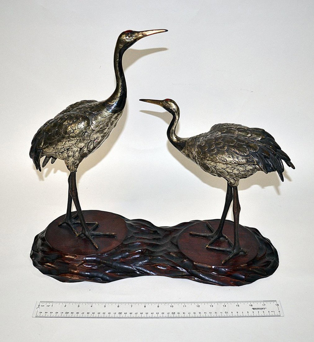 Japanese "Red Crowned" Crane Sculpture: Comprises two naturalistic modelled bronze-finish cranes on a carved cherry wood base. Each bear an enameled red "crown" on head. On mount: 21 1/2" W x 8 1/4" D x 18 1/2" H. One stamped "Japan" on bot
