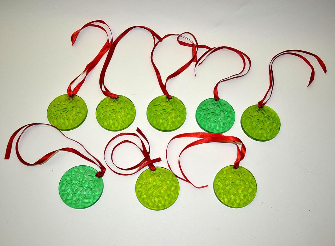 Set of 8 Lalique Holiday Ornaments: 8 mould-formed circular green crystal ornaments with holly branches and berry motif. 2 5/8"Dia. x 1/4" Deep. All in very good condition. Accompanied by original presentation boxes.