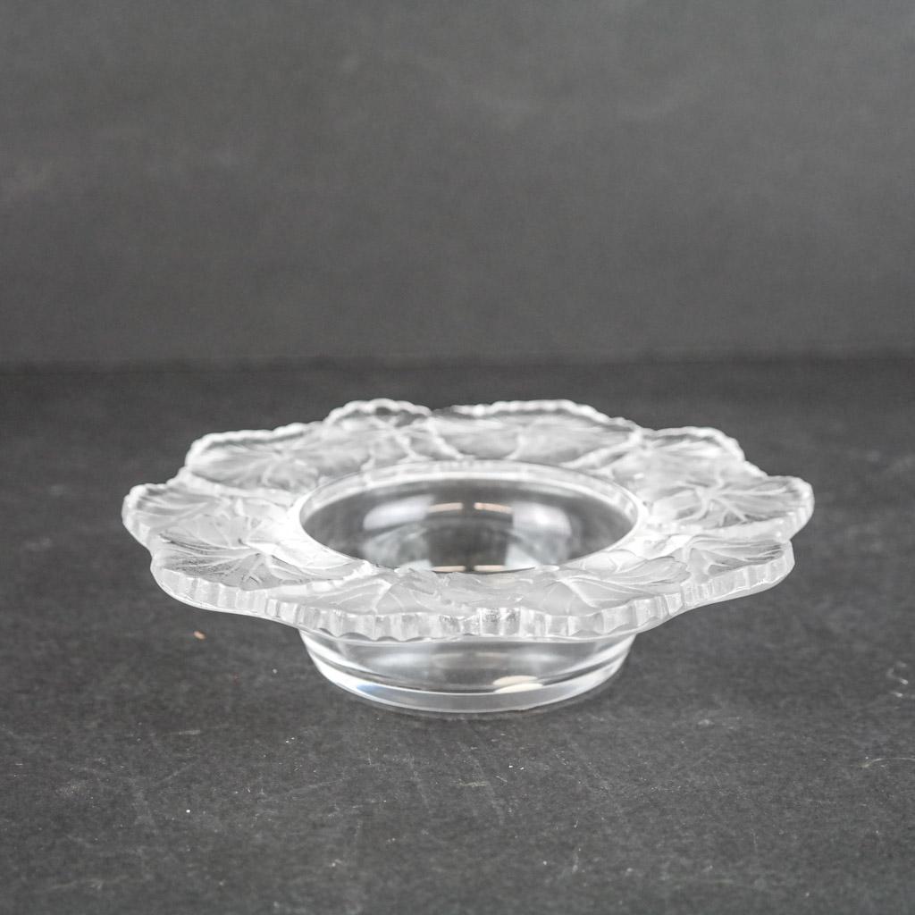 Lalique French Glass "Honfleur" Bowl: Lalique French glass "Honfleur" bowl with repeating foliate border above the dish, possibly an ashtray, bearing etched signature to base. [1 1/2" H x 5 7/8" Diam.]. Light abrasions; applied felt to ba