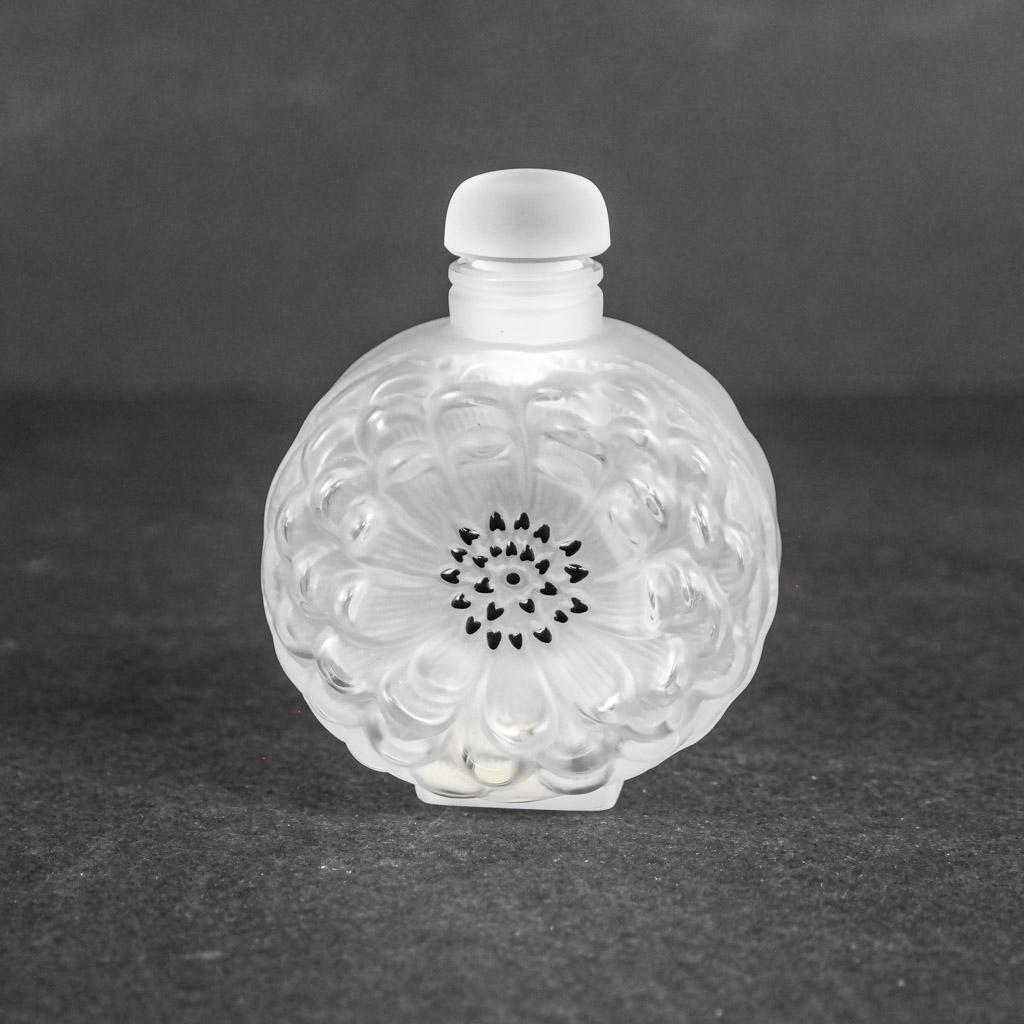 Lalique French "Dahlia" Perfume Bottle: Lalique French glass "Dahlia" perfume bottle, each side with floral motif, bearing etched signature to base. [3 1/2" H x 2 7/8" W x 1 3/4" D]. Stopper stuck; abrasions, stickers and adhesive residue t