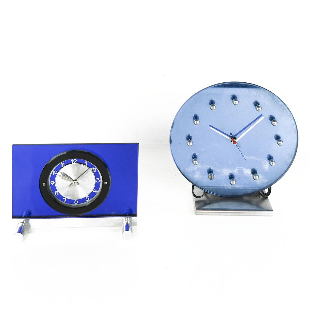 Art Deco-Style Desk / Table Clocks (2): Two Art Deco-style blue glass desk / table clocks, unsigned. [11" H x 10" W x 3 1/2" D; 6 3/4" H x 9" W x 2 3/4" D]. Rectangular clock with cracked black ring and small chips to edges; round clock wit
