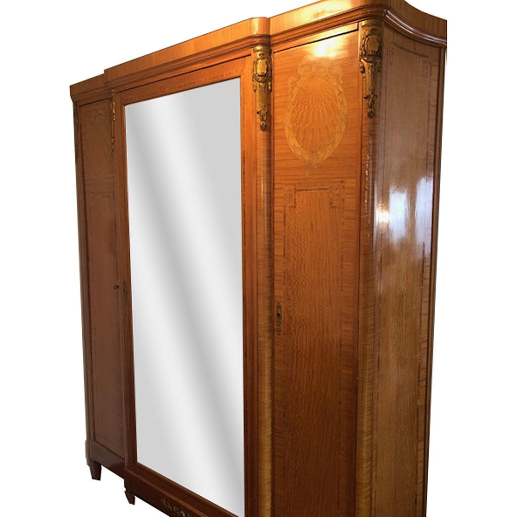 Louis XVI-Style Bronze-Mounted Armoire: Louis XVI-style bronze-mounted armoire, having mirrored center door, two marquetry inlaid satinwood and tulipwood doors, and bronze mounts, with shelving inside, circa 1920. [92" H x 72" W x 21" D].