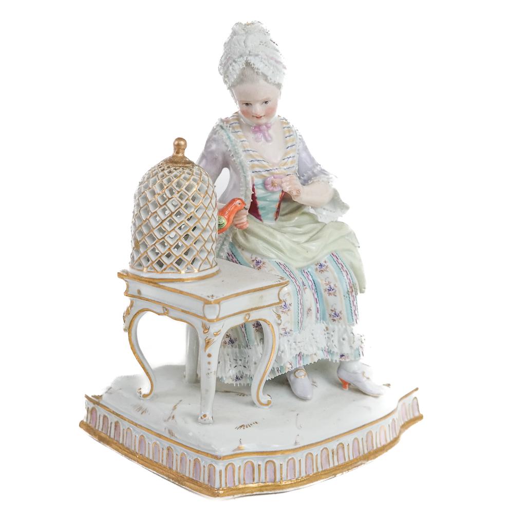 Meissen Porcelain Group "Sentiment": "Sentiment" group by Schonheit, of a woman seated next to a bird peeking from a birdcage. Heavy in the hand. [6" H x 4" W x 3 1/2" D].