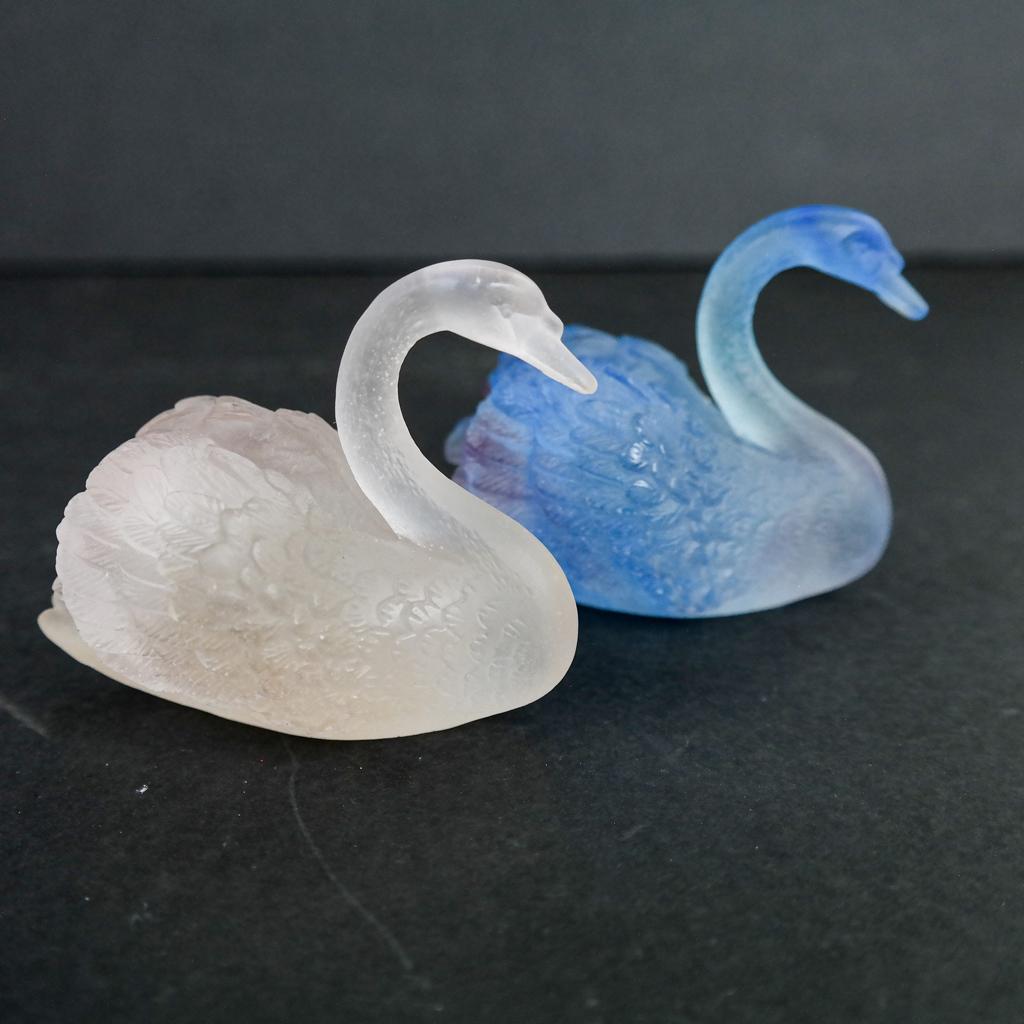 Pair of Daum "Pate de Verre" Swans: Pair of Daum swans, one in blue tones, the other in opaque white glass, both signed "Daum, France" to undersides. [2 1/2" H x 3" W x 2 1/4" D]. In good condition.