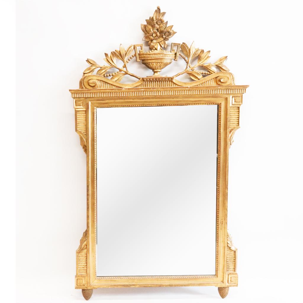Friedman Brothers Louis XVI-Style Mirror: Freidman Brothers Louis XVI-style giltwood mirror in the Neoclassical manner, with urn, floral and foliate details. [58" H x 34" W]. Losses to carving and decoration.