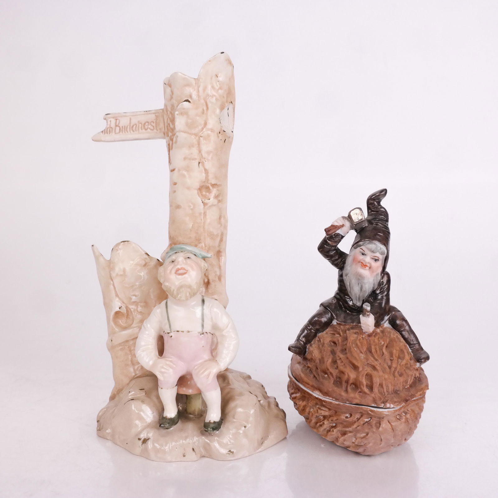 Two "Gnome" Subject Porcelain Figurines: Two gnome-form porcelain figures, one as a flower vase, the other a bisque boy with a cover in the form of a nut being cracked. [7 3/4" H x 4" Diam.]. In good condition.