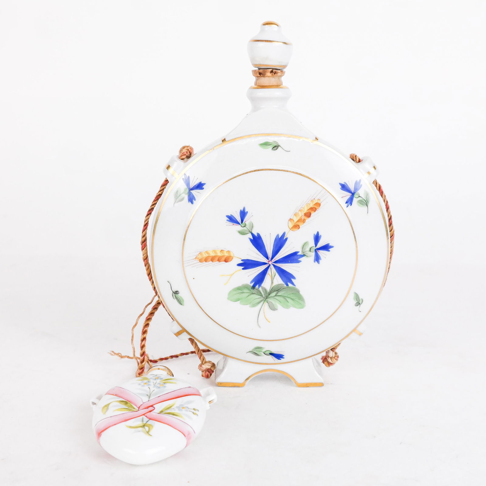 Two Porcelain Flasks, One "Tata, Hungary": Two porcelain flasks with floral decoration, the larger one marked with logo of "Tata, Hungary", modeled as a footed pilgrim flask [6 1/2" H x 4 1/2" W x 1 1/2" D], the other a corked scent flask with