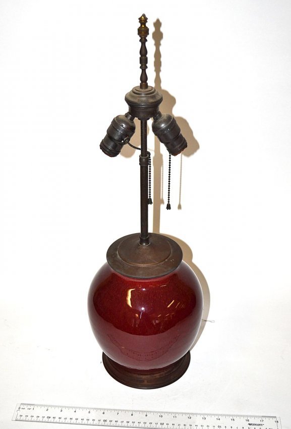 Chinese Sang de Boeuf Lamp: Ovoid jar-form lamp with circular carved wood base: 26" H to finial. In very good condition.