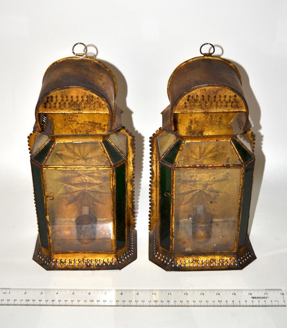 Pair of Antique Tole Lanterns: Glazed gilt tole lanterns with pierced bases and scalloped edges. Each feature stamped double-star backplates. 7" W x 4 1/4" D x 13 3/4" H. In good antique condition.