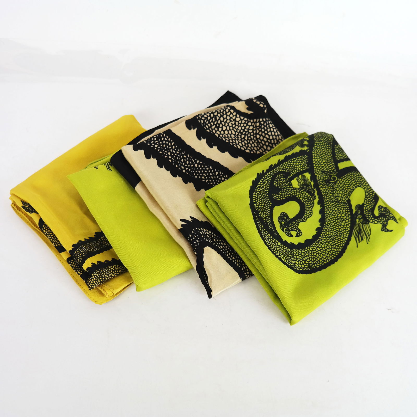 Donald BROOKS: Four Vintage Chinese Dragon Scarves: Four vintage Donald Brooks (American, 1928-2005) dragon illustrated Chinese serpent square scarves, including two green cotton, one white silk, and one yellow silk. Provenance: Proceeds of the sale of