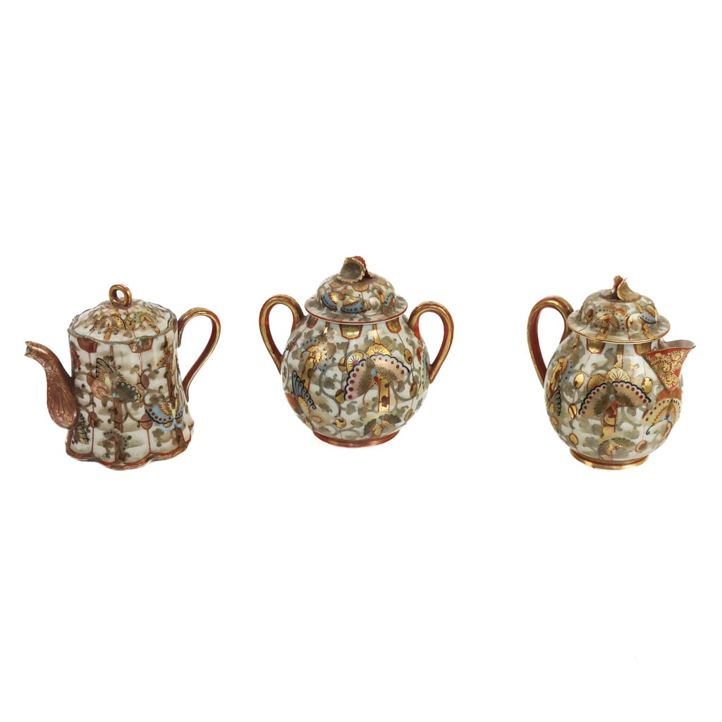 Japanese Kutani Satsuma Porcelain Articles (3): Japanese Kutani Satsuma porcelain articles , late 19th - early 20th century, including a teapot, sugar bowl and cream pitcher, with gilt-accented scrolling details with butterflies, bearing marks to b