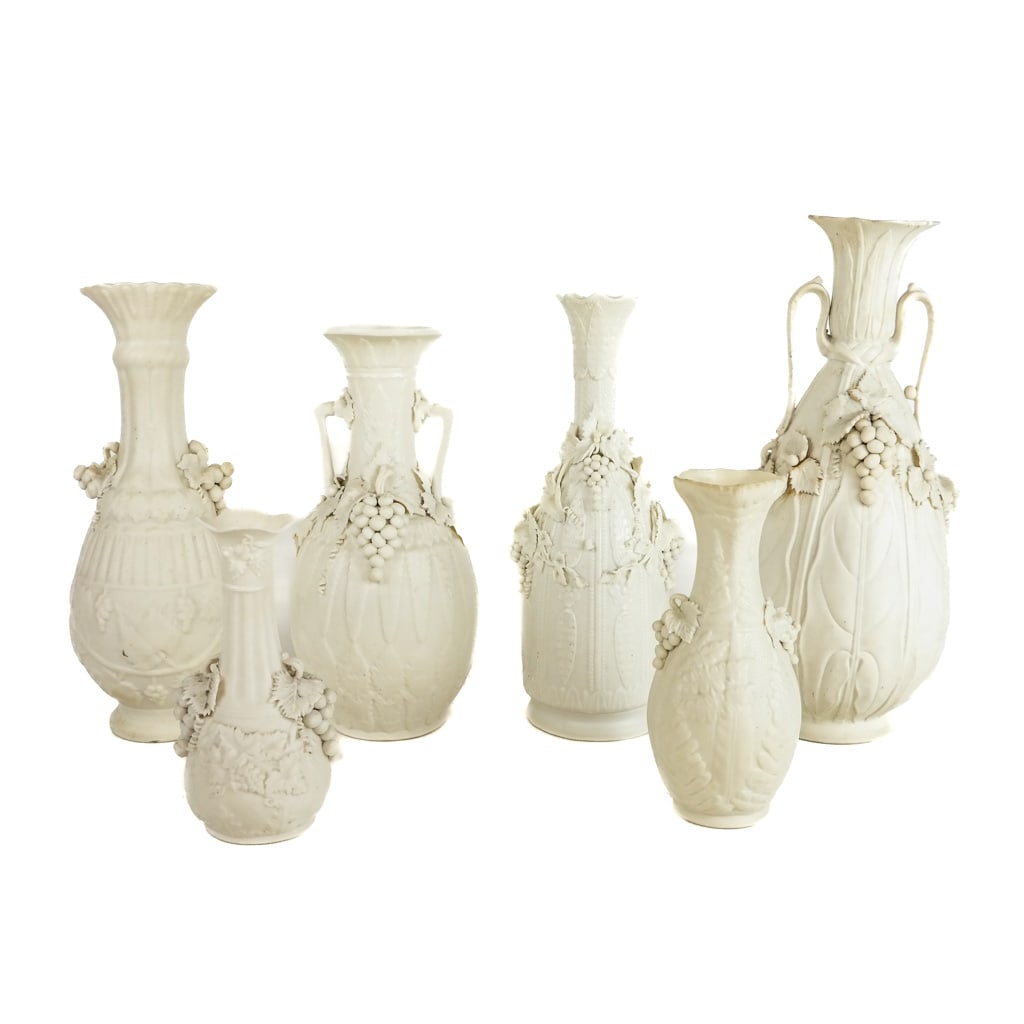 Group of 6 Parian Porcelain Relief Vases: Group of 6 parian porcelain relief vases, each with Bacchanalian motifs of grapes and leaves, in the manner of Bennington; unmarked. [Tallest: 10 3/4" H x 5 1/2" Diam.]. Chips to leaves and rims; some