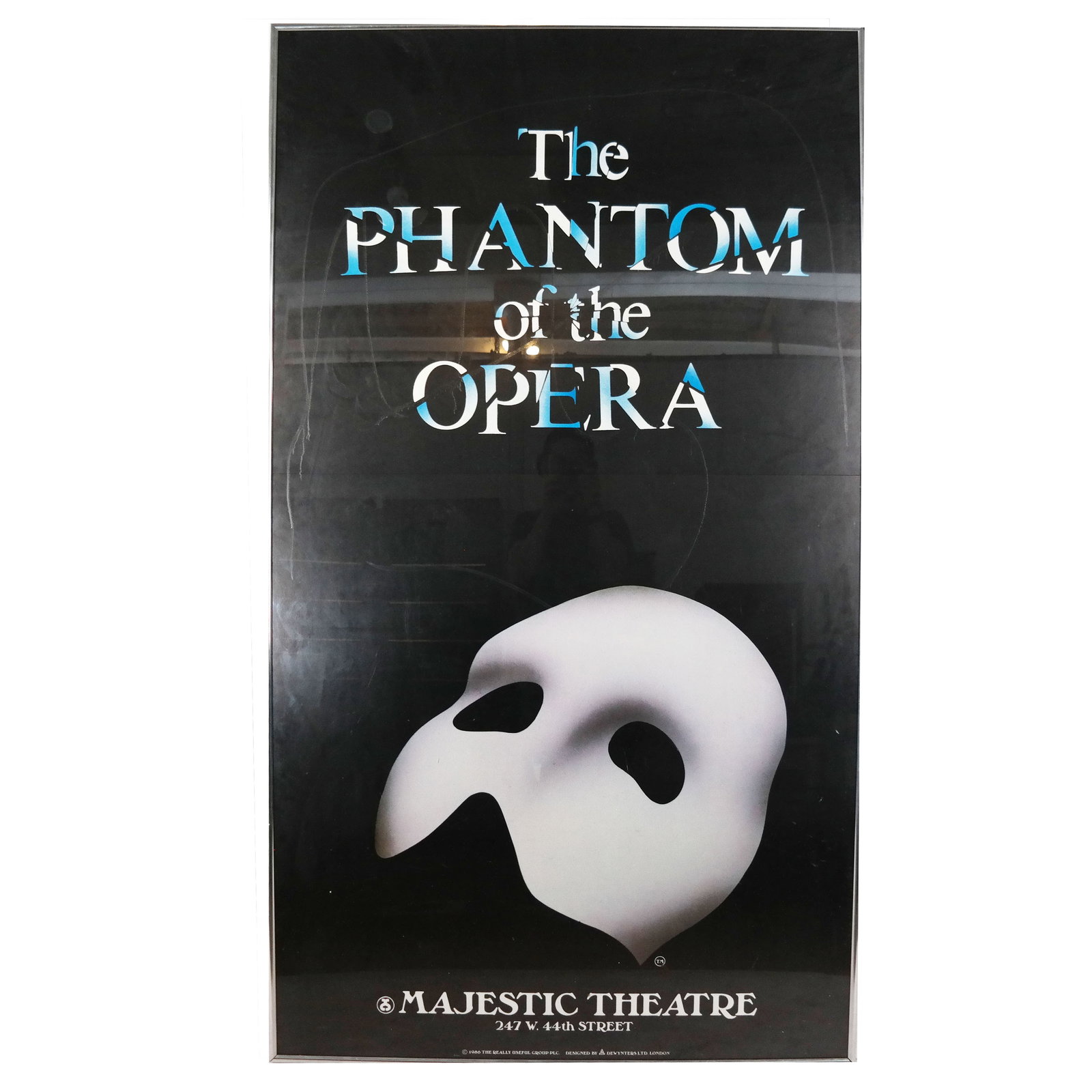 Poster: The Phantom of the Opera: Advertising poster for the long-running Broadway show "The Phantom of the Opera" dated 1986. [Frame: 72 x 40 inches]. Fold crease across center, stains and marks to Plexiglass.