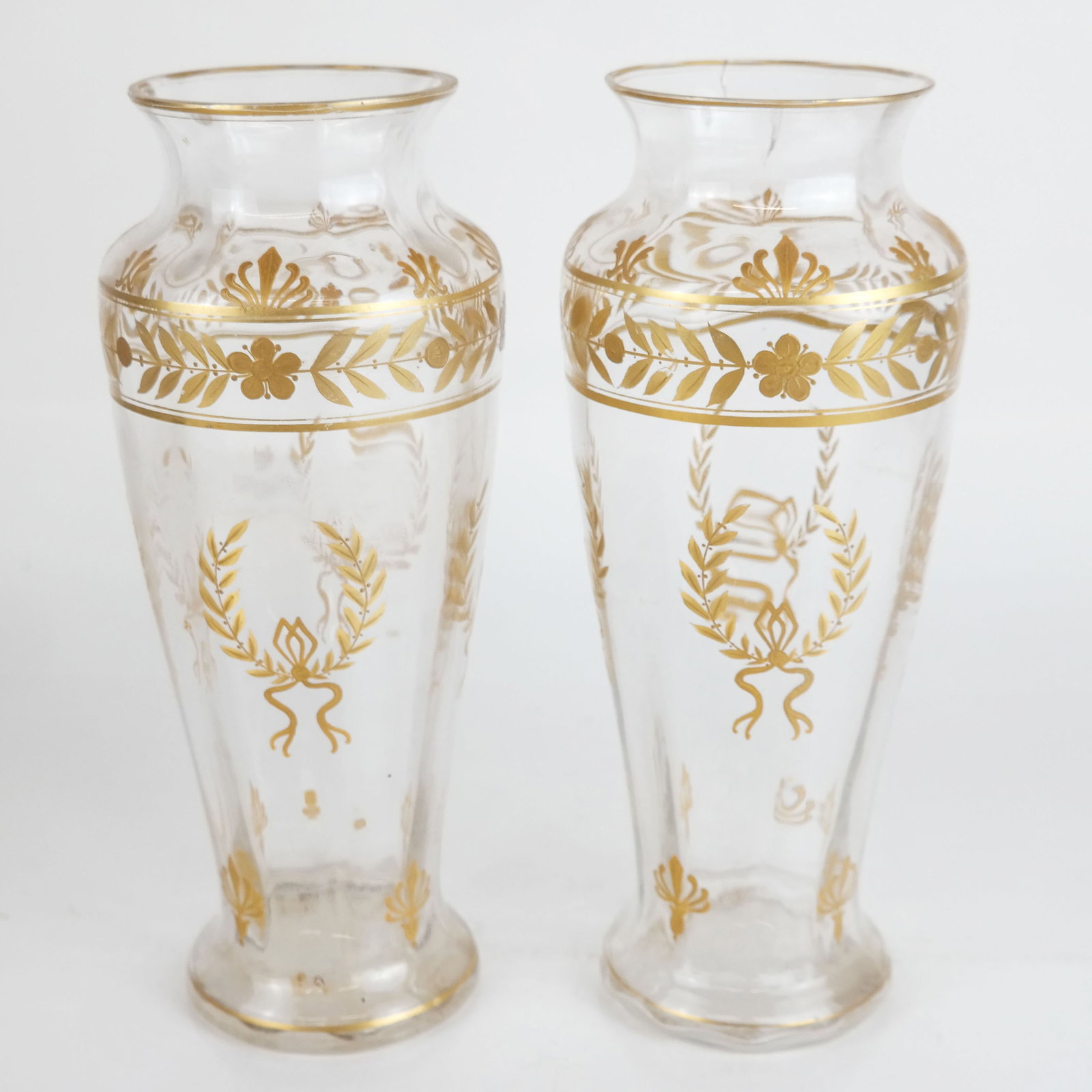 Pair of Napoleon III Parcel Gilt Glass Vases: Pair of 19th century French Napoleon III parcel gilt glass vases, overall with painted Neoclassical motifs of laurel leaf wreaths, palmettes, and floral details. One with cracked rim, both with light 