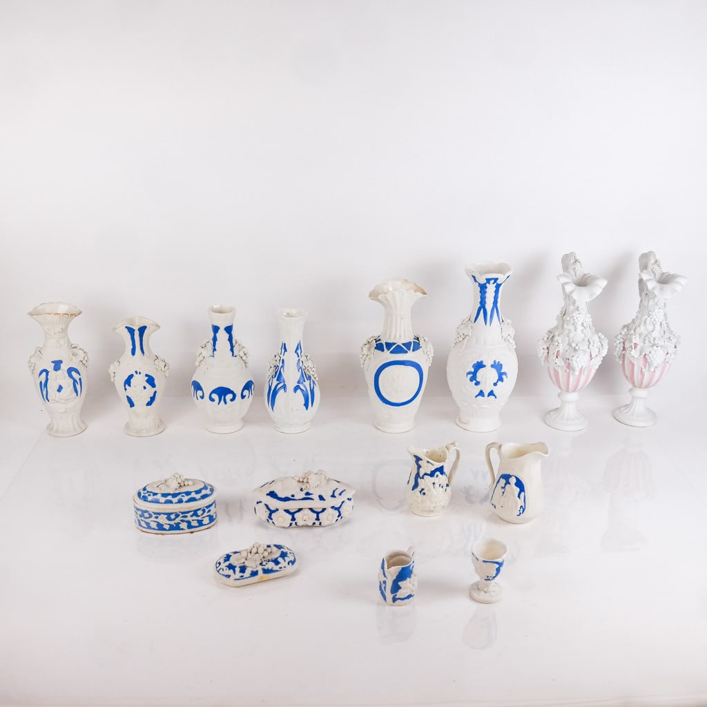 Group of Fourteen (14) Parian Porcelain Articles: Group of fourteen parian porcelain articles, including vases and other items with relief details, in the manner of Bennington, with applied blue or pink paint decoration. [Tallest: 10 1/2" H x 5" Diam