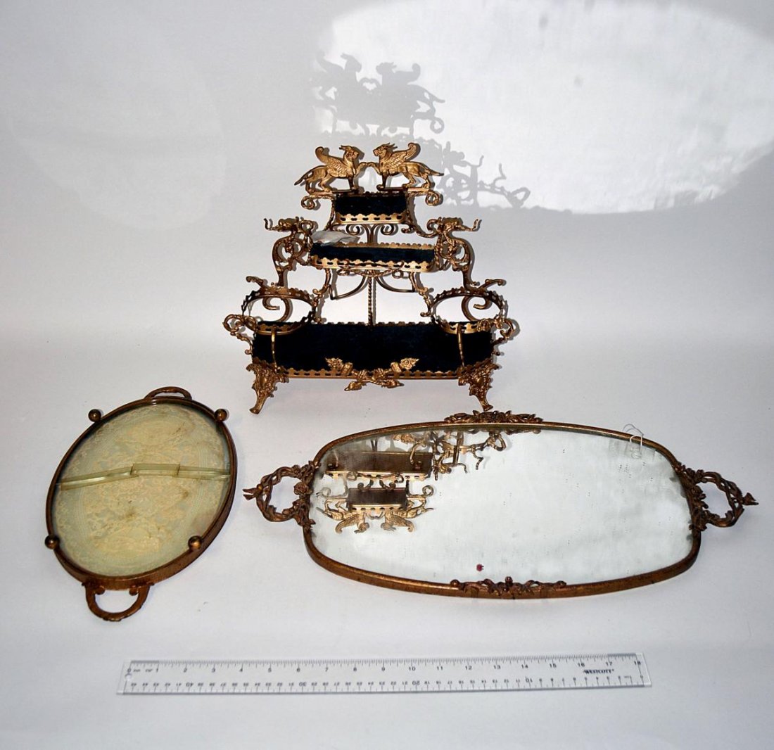 Three Brass Articles: Mirror vanity tray, footed tray, and a bottle holder. 13" - 21 1/2" L x 11 1/2" H.