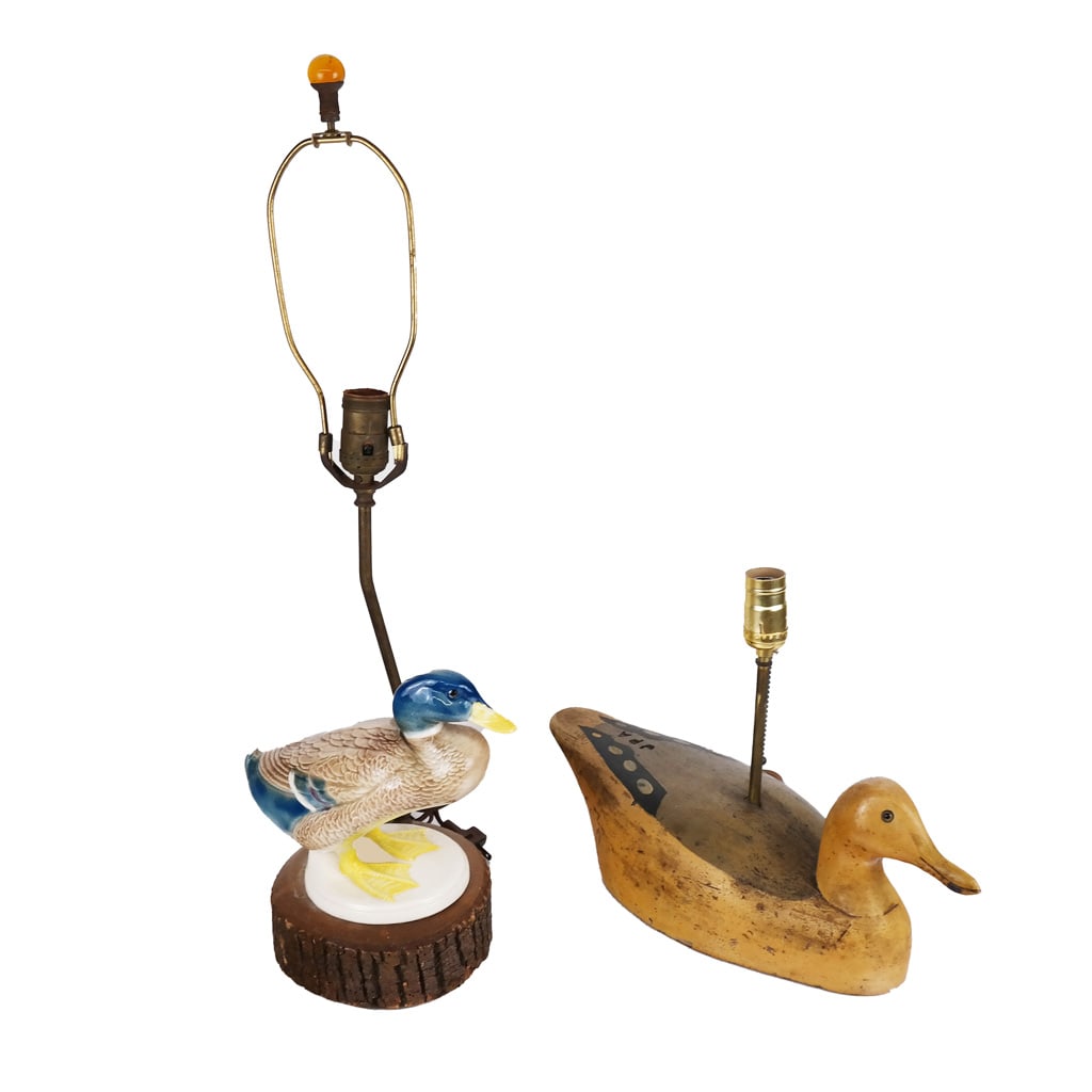 Two Duck-Form Lamps: One porcelain duck as lamp, the other a wooden duck decoy as lamp, JPA, drilled. [7 inches duck only, 7 x 17 inches; 17 inches H to socket, and the other 12 inches H to socket].