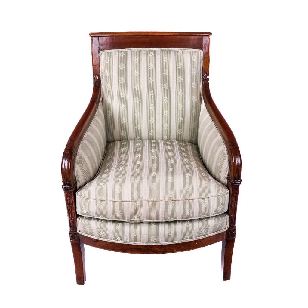 Biedermeier Carved Mahogany Bergere: Biedermeier carved mahogany bergere, early 19th century, German or Austrian, the armchair with foliate details around striped upholstery. [33 1/2" H x 24 1/2" W x 23" D]. Patched restoration.