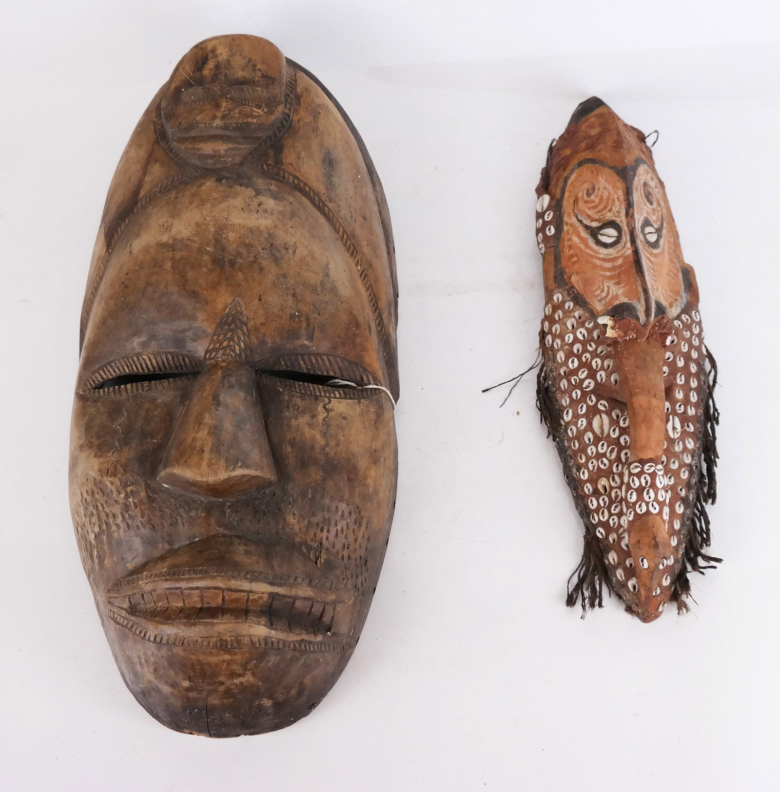 African Carved Wood Tribal Masks: One with shell details. Provenance: Tepper Galleries Lot Tag. [Larger: 19 x 9 1/2 x 4 1/4 inches]. Losses, marks, wear.