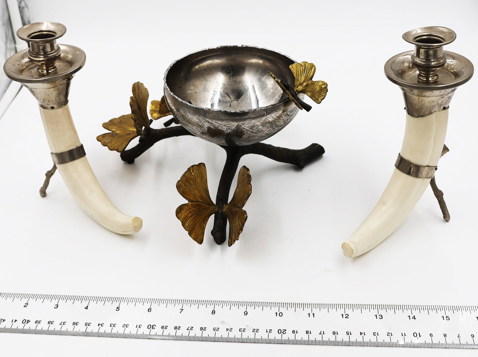 Three Tabletop Decorations: Pair of faux tusk and chrome candlesticks [7" H] and a mixed metal bowl on branch-style base with butterflies. Provenance: Estate of Monique Van Vooren.