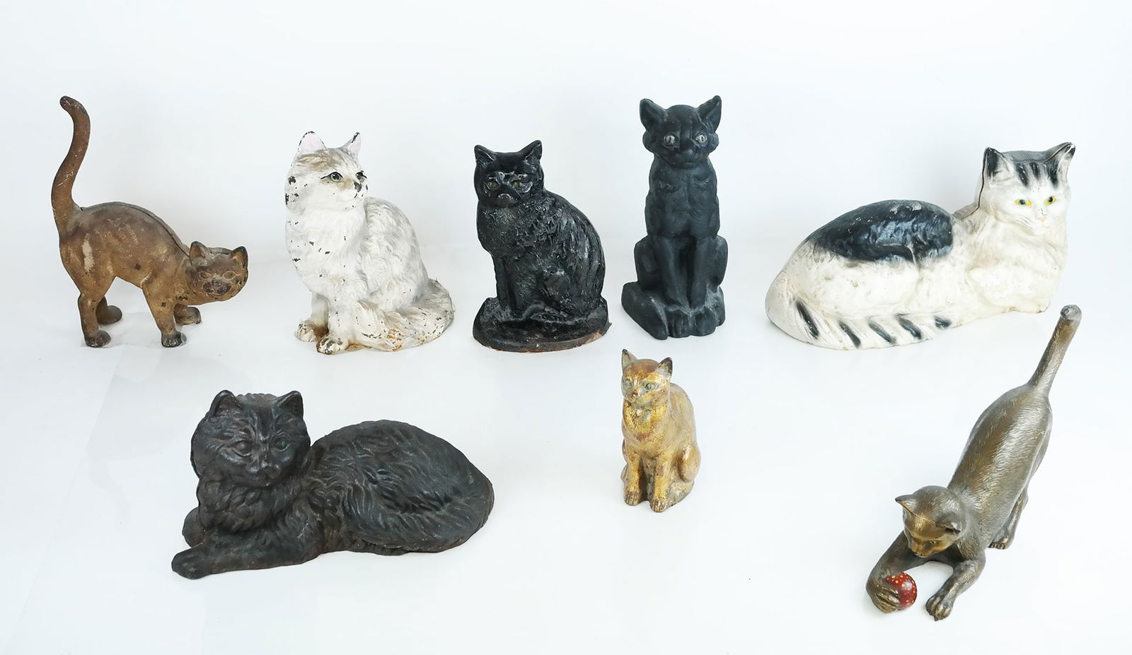 Assembled Group of Bronze & Iron Cats (8): Assembled group of bronze and iron cats, early to mid-20th century, comprising sculptures and doorstops. [Largest: 7 1/4" H x 14" W x 5 1/4" D]. Some with wear to paint and patina; marks and residue.