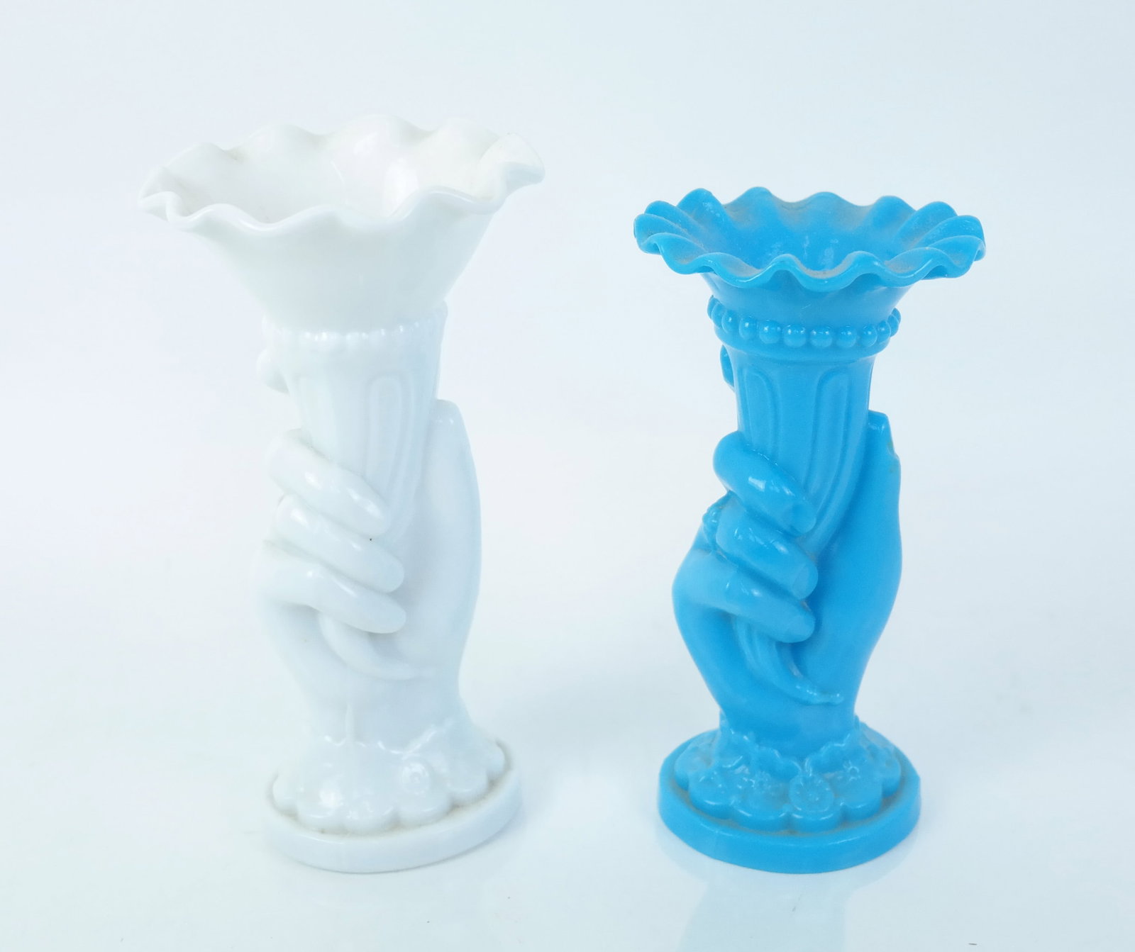 Two Vintage Opaline Glass Vases: Two vintage opaline glass vases in the form of a hand holding a cornucopia upright, one in blue and one in white. [Blue: 7 1/2" H x 4" Diam.; White: 8 1/4" H x 4 1/2" Diam.]. Both in good condition.