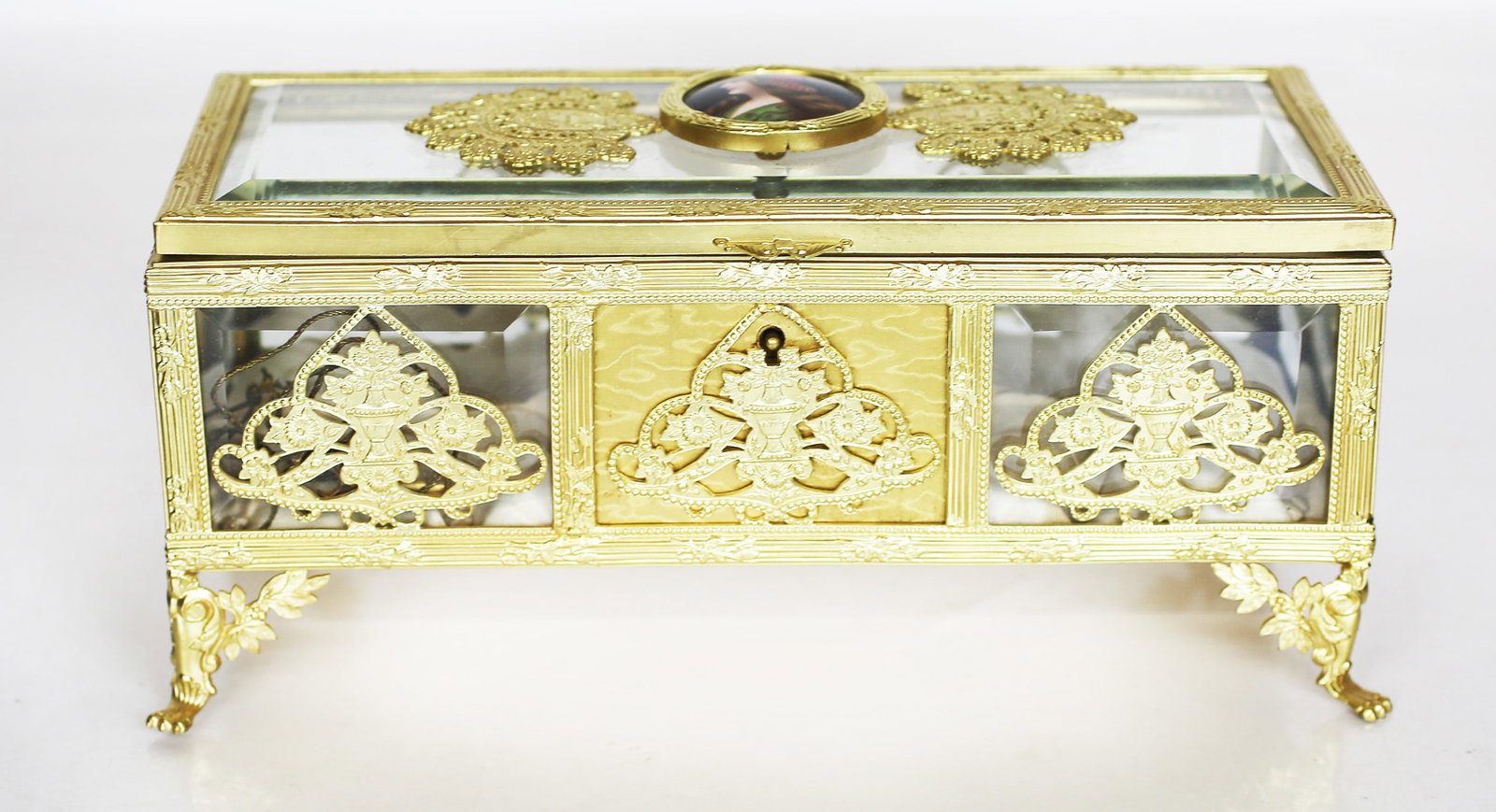 Continental Gilt Metal & Glass Jewelry Box: Continental gilt metal and glass jewelry box, the beveled glass top centered with a painted medallion of a maiden, possibly Esther or Gitina, in the manner of F. Wagner, overall with Classical urn and