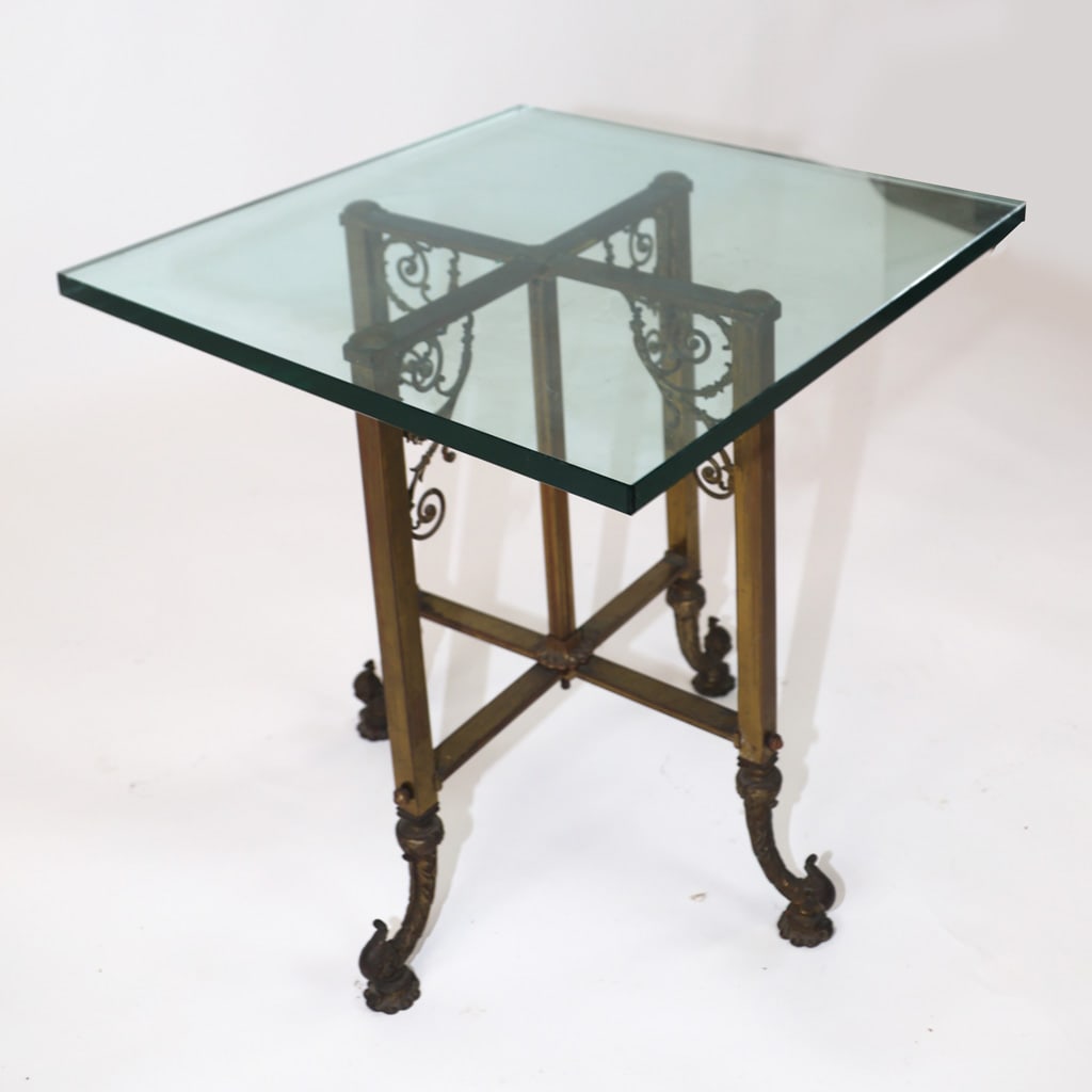 Belle Epoque Gilt Metal & Glass End Table: Belle Epoque gilt metal and glass end table, circa 1900, the square top over the base with scrolling details. [21 1/4" H x 20" W x 20" D]. Glass probably later; oxidation and wear to base.